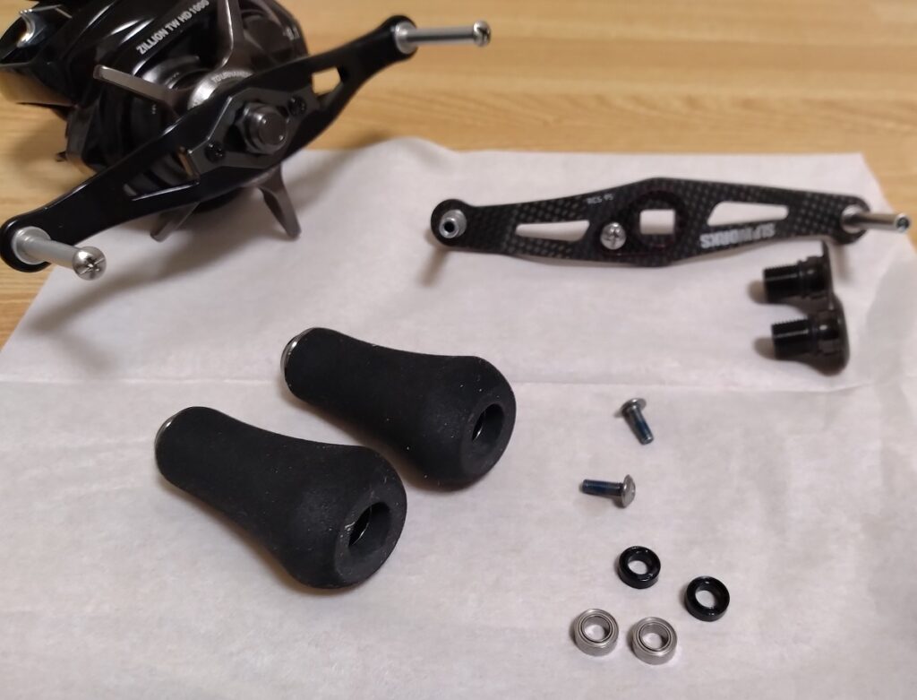 22 ZILLION TW HD、とても好き何だけど、ハンドルの長さだけが違和感が有り、使いなれた95㎜カーボンハンドルに交換しました。
ハンドルノブのキャップは、へこみに丸ペンチを差し込んで、押さえながら、逆ネジなので、右に回すと外れるので、中に有る、マイナスネジを外すと、取れます、小さな+ドライバーでも可能ですが、硬くてなめやすいので、マイナスドライバーがおすすめ、ついでに、ベアリング追加も行いました。